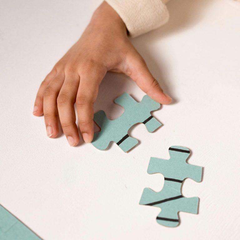 Kind beim Puzzeln – Spielerische Therapieansätze in der Kinder- und Jugendlichenpsychotherapie Ein Kind hält zwei große Puzzleteile in der Hand und versucht, sie zusammenzusetzen.